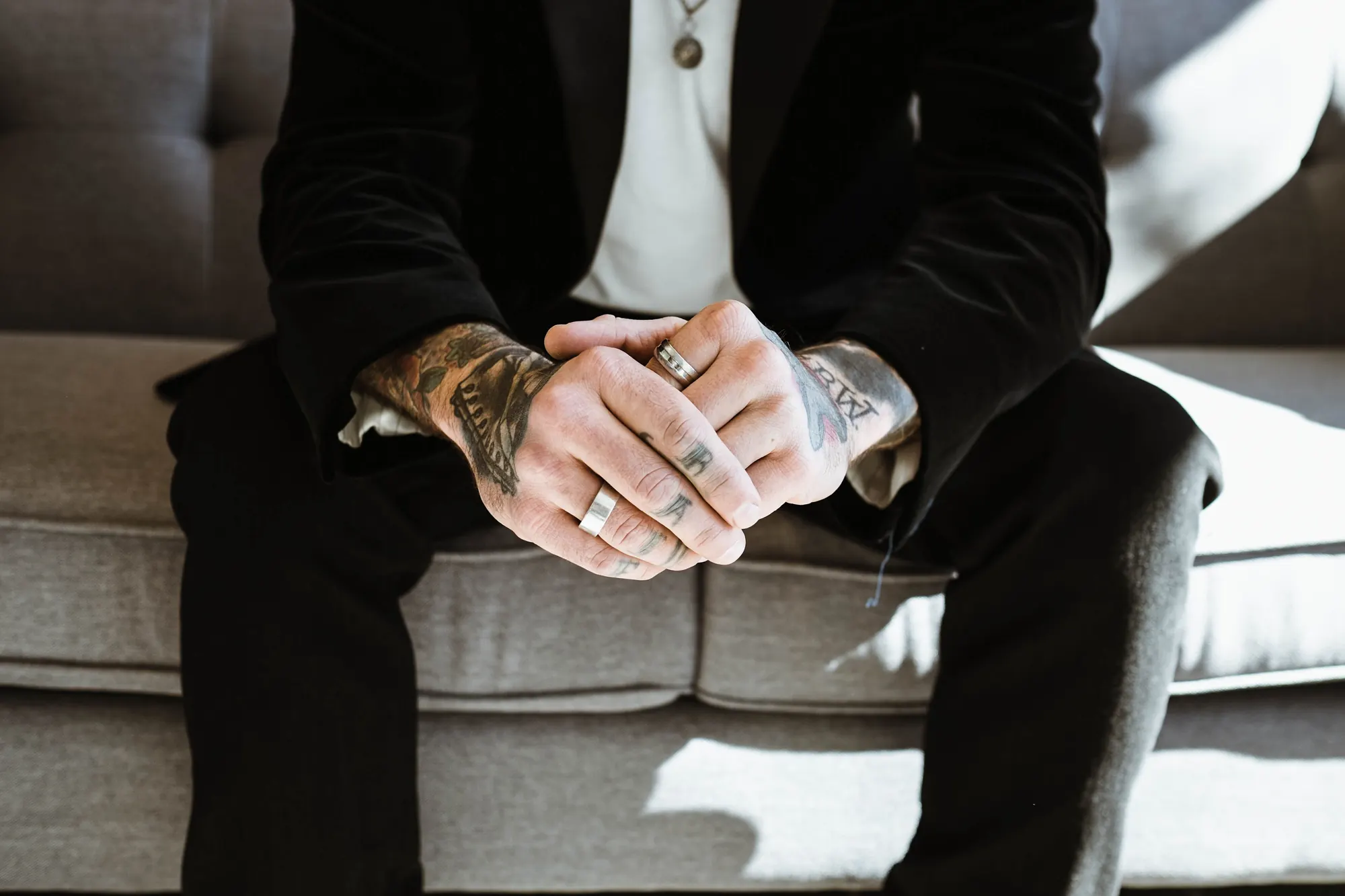 Tattooed hands resting on a tailored suit